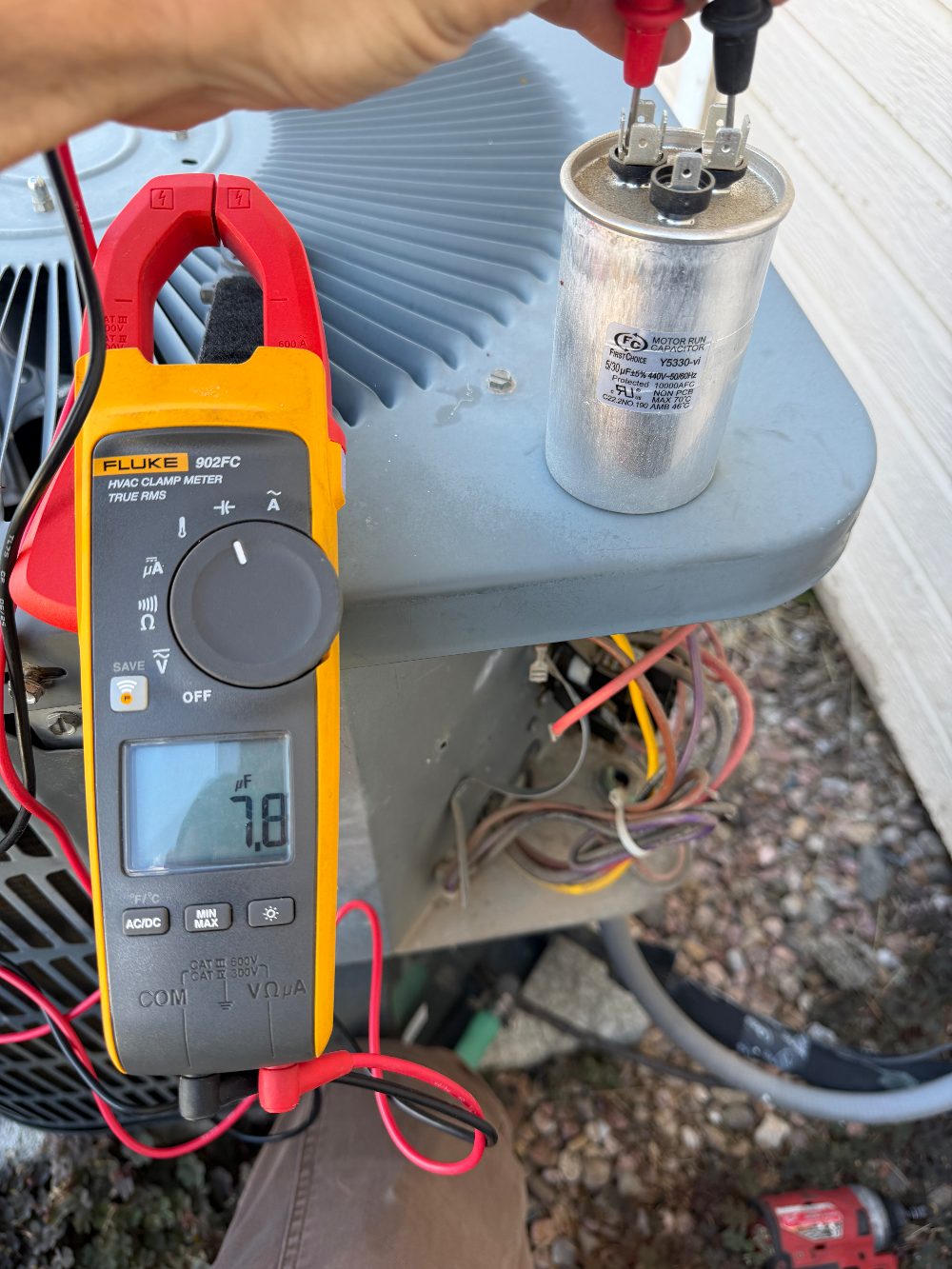 Testing an AC dual run capacitor with an HVAC clamp meter, reading out of spec against its printed rating