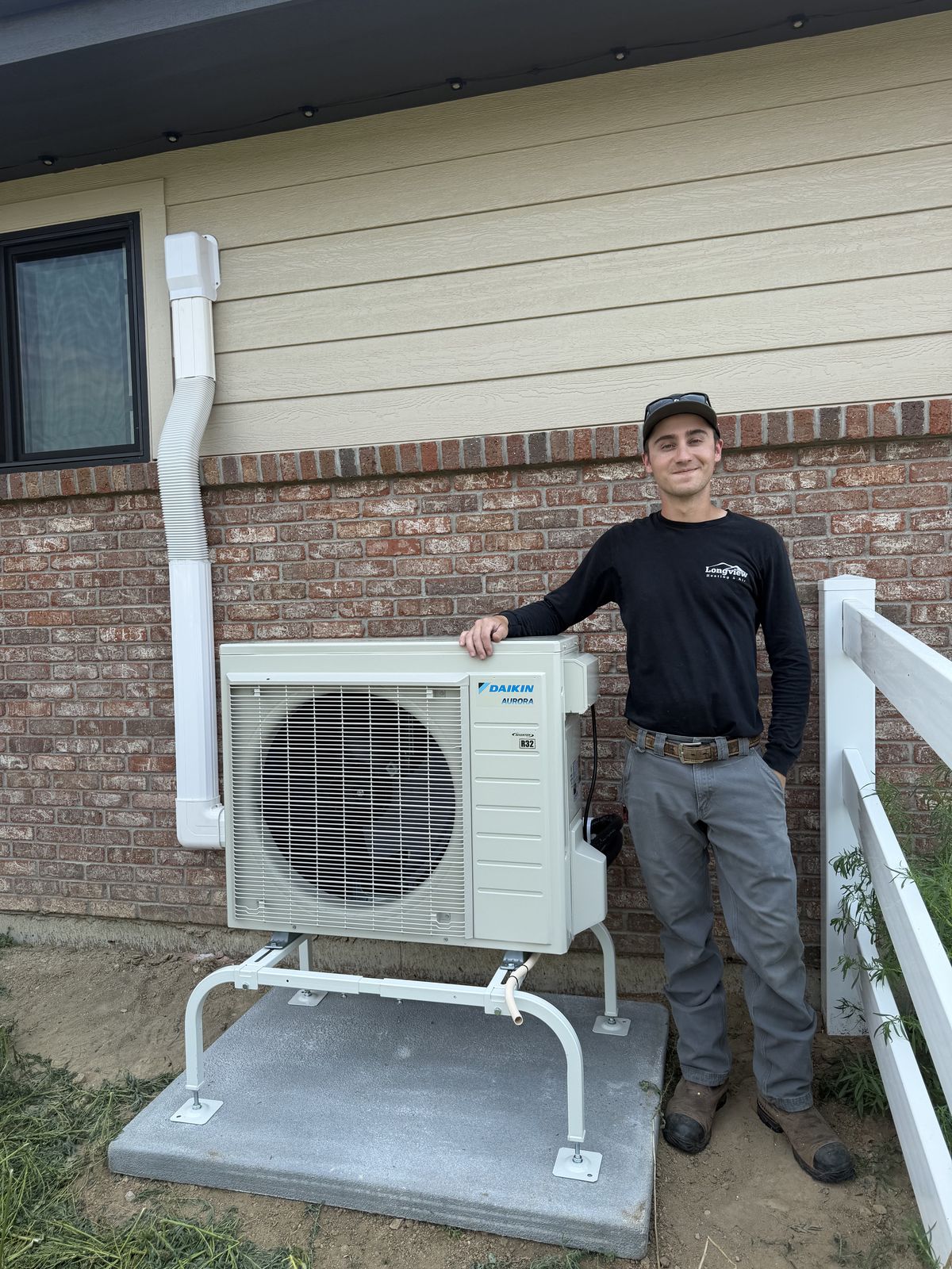 Longview Heating & Air technician beside a completed Daikin Aurora ductless heat pump outdoor unit